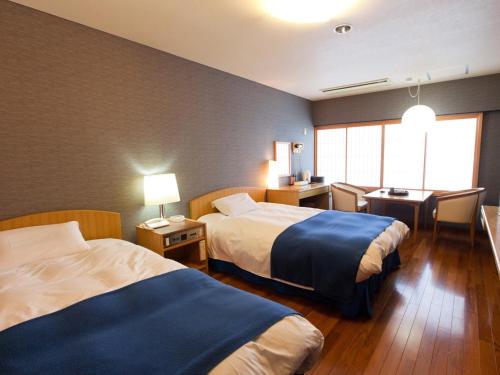 ein Hotelzimmer mit 2 Betten und einem Schreibtisch in der Unterkunft Sansuien in Kōchi