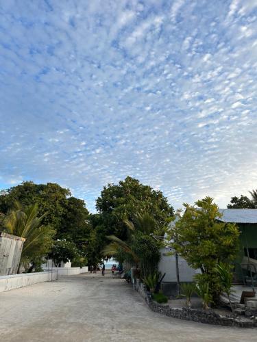 a road with trees and a cloudy sky at Atholhu Residence in Fehendhoo