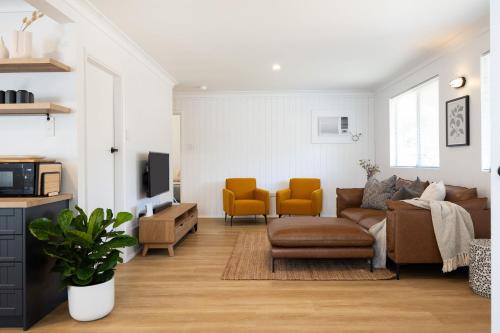 a living room with a couch and two yellow chairs at Barney's Beach House Narrawallee in Narrawallee