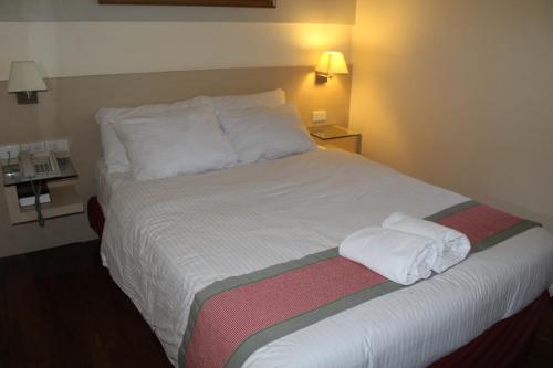 a bed in a hotel room with white sheets and pillows at Ciudad Fernandina Hotel in Vigan