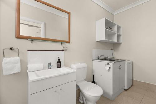 a bathroom with a toilet and a sink and a mirror at Kingston Gardens by Experience Jervis Bay in Huskisson