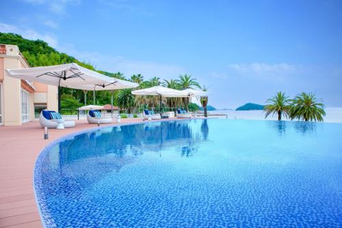 a large swimming pool with chairs and umbrellas at MARISSA RESORT sazanseto suo-oshima in Suo Oshima