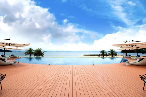 a pool with chairs and umbrellas and the ocean at MARISSA RESORT sazanseto suo-oshima in Suo Oshima