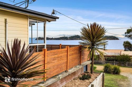 a fence in front of a house with a view of the water at Island Escapes in Alonnah