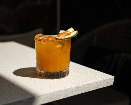a drink sitting on a table with a slice of lime at The Xperience by g in Mazatlán