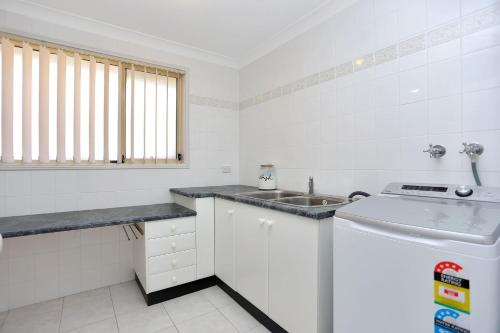 a small white kitchen with a sink and a counter at Coastal Calm Pet Friendly in Tea Gardens