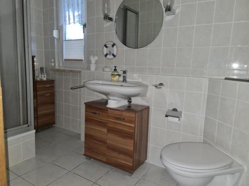 een badkamer met een wastafel, een toilet en een spiegel bij Ferienhaus Elbe -Parey am See in Parey