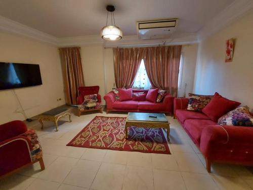 uma sala de estar com sofás vermelhos e uma televisão em كمبوند ابراج الخليج علي النيل no Cairo