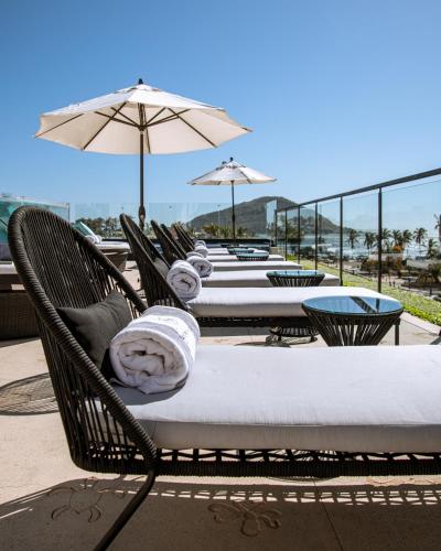 a row of tables with chairs and umbrellas at The Xperience by g in Mazatlán