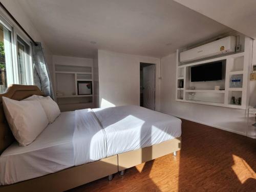 a bedroom with a large white bed and a television at Lake Hill Resort Kanchanaburi in Tha Kradan