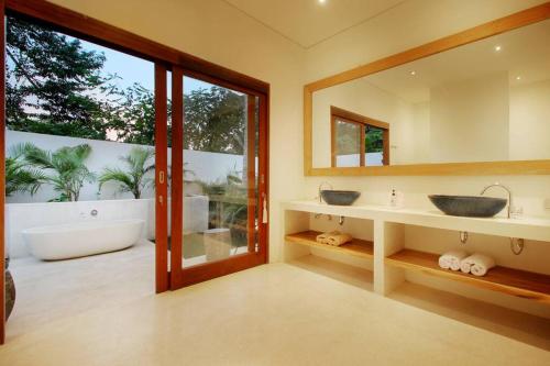 La salle de bains est pourvue de 2 lavabos et d'une grande fenêtre. dans l'établissement Modern and stylish 3 Bedroom Villa, à Ubud
