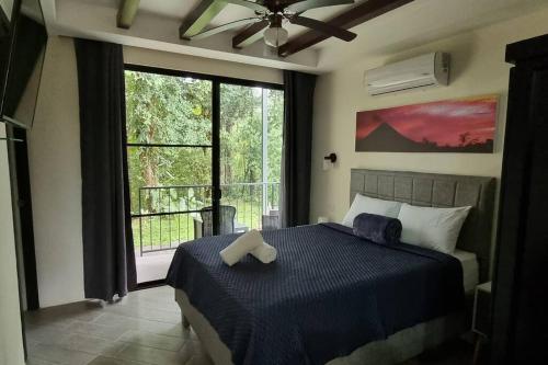 um quarto com uma cama e uma grande janela em Villas Töcu - Casa Colibrí em La Fortuna