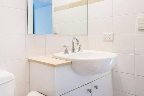 a white bathroom with a sink and a mirror at Garden Terrace, Pool & Gym - Trendy Hideaway in Sydney