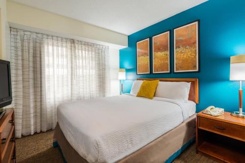 a bedroom with a bed and a blue wall at Residence Inn Charlotte SouthPark in Charlotte