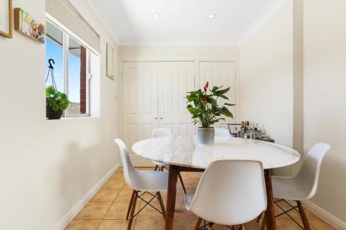 a white dining room with a table and white chairs at Randwick l 3 Bedroom Apartment + Parking in Sydney