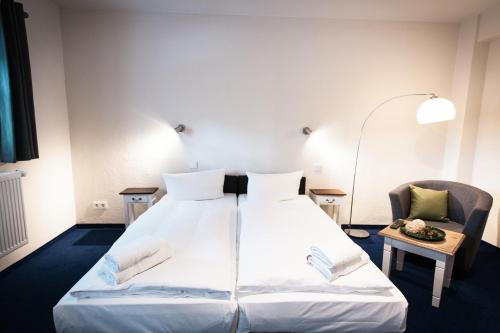 a hotel room with a large bed and a chair at Arcade Hotel & Hostel Hamburg in Hamburg