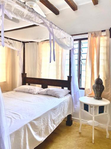 a bedroom with a white bed and a table at Beautiful Mafriza Apartment in Lamu