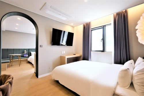 a hotel room with a white bed and a mirror at De Lamour Hotel in Tongyeong