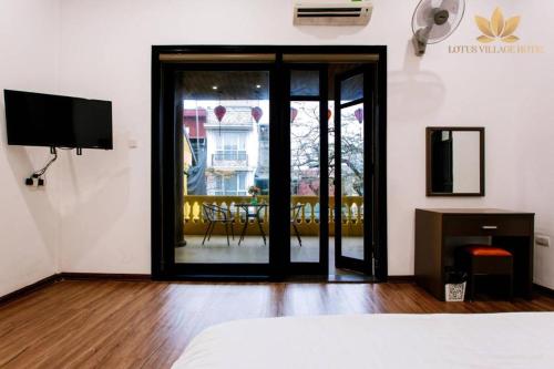 a room with a bed and a television and a table at Lotus Village Hotel - 68 Hàng Bồ - by Bay Luxury in Hanoi