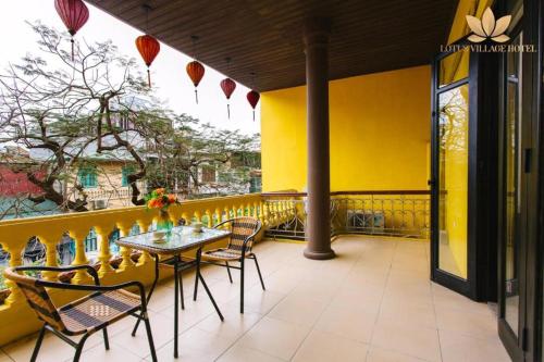 a table and chairs on a balcony with a yellow wall at Lotus Village Hotel - 68 Hàng Bồ - by Bay Luxury in Hanoi