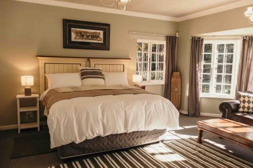 a bedroom with a bed and a chair and windows at Milestone Farm House in Balgowan