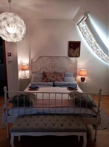 a bedroom with a large bed with a chandelier at Vendégház a Csabay Kúriához in Lakitelek