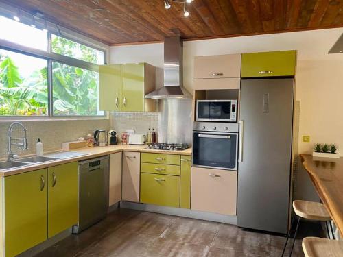 uma cozinha com armários amarelos e verdes e um lavatório em Villa Hoama Lodge Moorea em Teavaro