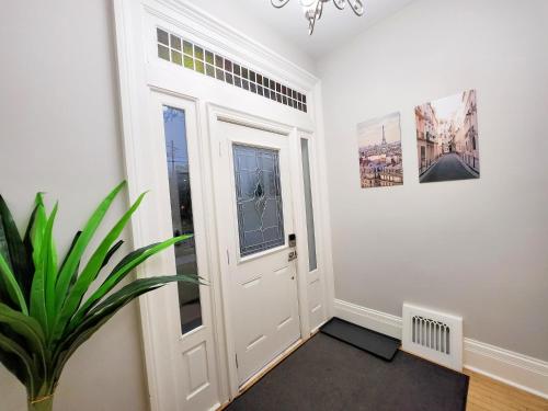 a hallway with a white door and a plant at The Zen Escape Modern Queen Size One Bedroom Full Apartment in St. Catharines