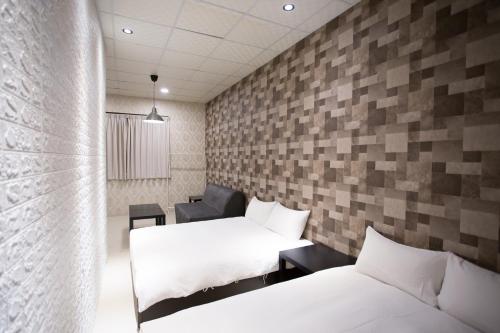 a room with two beds and a wall with tiles at 逢希小宿 in Taichung