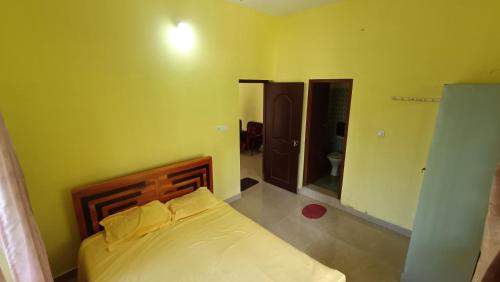 ein Schlafzimmer mit einem Bett in einem gelben Zimmer in der Unterkunft Pebbles in Kozhikode