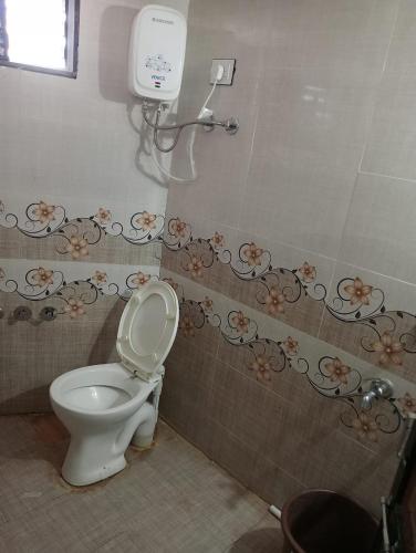 a bathroom with a toilet and a hair dryer on the wall at SARDAR HOME STAY in Garudeshwar