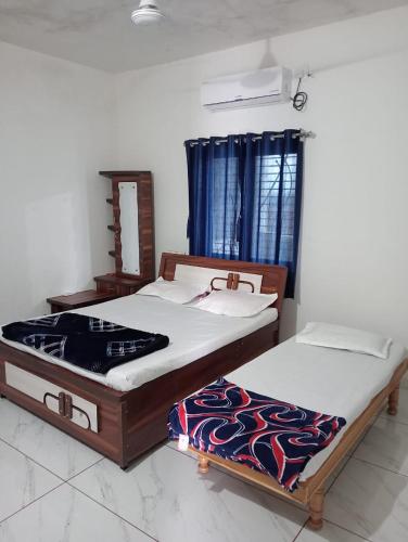 two twin beds in a room with a mirror at SARDAR HOME STAY in Garudeshwar