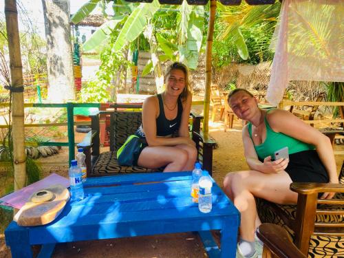 錫吉里亞的住宿－Reggae paradise hostel，坐在蓝色桌子旁的椅子上的男人和女人