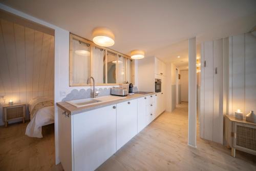 una cucina con armadi bianchi, lavandino e letto di Les Voiles - Appart'hotel "Le Sein" a Carnac