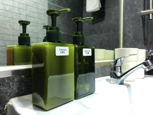 two green bottles sitting on top of a bathroom sink at 香港星星旅馆 2202 Guesthouse in Hong Kong