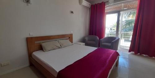 a bedroom with a bed with purple curtains and a window at Coco Lux Studio Grand Baie in Grand Baie