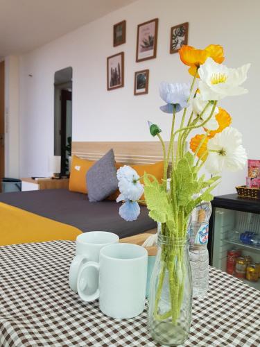 a vase of flowers sitting on a table with cups at Libré Homestay in Hanoi