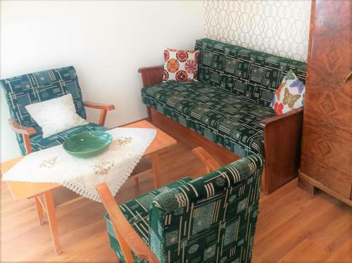 a living room with a table and a green couch at Vendégház a Csabay Kúriához in Lakitelek
