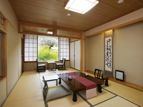 a room with a table and chairs and a window at Kisoji no Yado Iwaya in Kiso