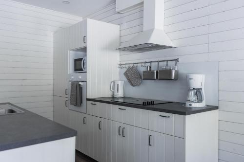 una cucina con armadi bianchi e piano cottura di Arctic Holiday Apartments 1 a Rovaniemi