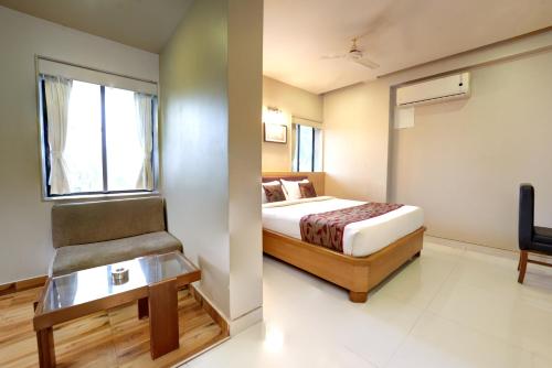 a bedroom with a bed and a chair and a window at Hotel Prestige, Mangalore in Mangalore