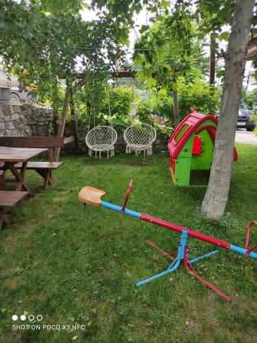 a childs play equipment in the grass next to a tree at Vila Čair DOPLATA ZA BAZEN in Soko Banja