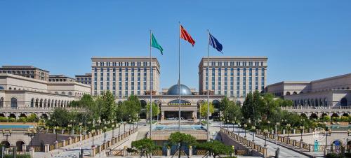 two flags are flying in front of a building at GUOCE Beijing Capital Airport Hotel & Convention Center in Shunyi
