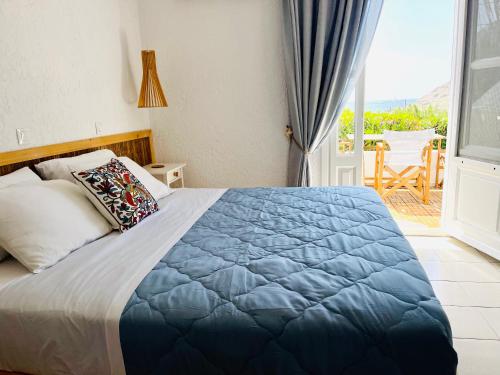 um quarto com uma cama com um cobertor azul e uma varanda em Seaside Studios em Arkasa