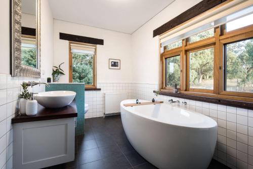 een badkamer met een bad, een wastafel en ramen bij Three Paddocks in Bullarto