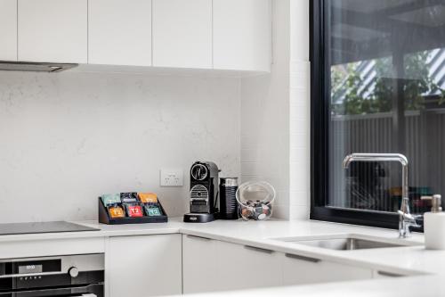 a kitchen with white cabinets and a sink and a window at Vale 194 - Luxury Accommodation in McLaren Vale - 5 holiday homes with king size beds in McLaren Vale