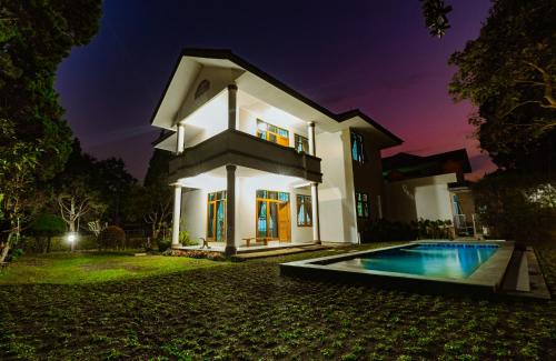 une villa avec une piscine la nuit dans l'établissement Andaru Graha Puspa For Family and Friends, à Bandung
