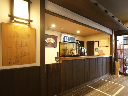 a restaurant with a bar with a fish tank on the wall at Kisoji no Yado Iwaya in Kiso