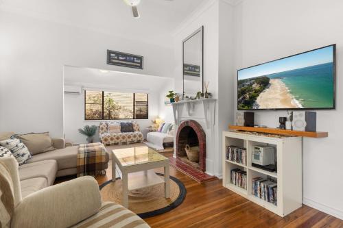 a living room with a fireplace and a tv at Kingston Cottage by Experience Jervis Bay in Huskisson