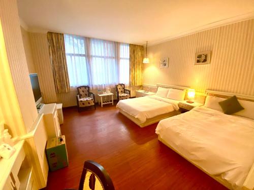 a hotel room with two beds and a television at Li Hua Hotel in Taoyuan